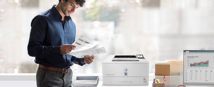 Man standing by TROY 4001 MICR printer and examining documents