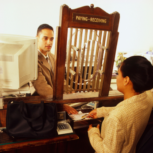 Bank teller helping a customer in old fashioned teller window 