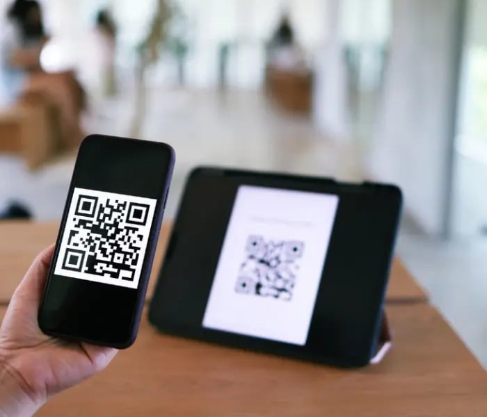 Person scanning QR code on tablet with iPhone 