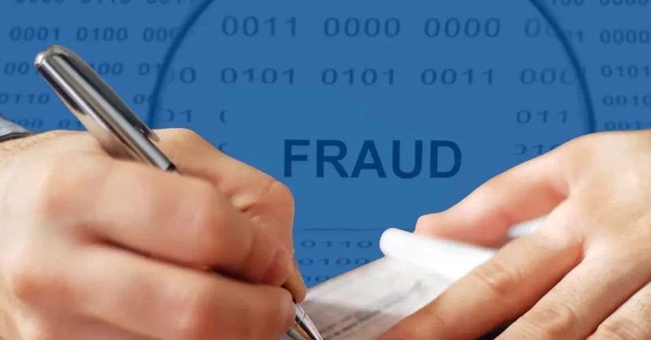 Two hands writing a MICR ink printed check with the word Fraud in the background