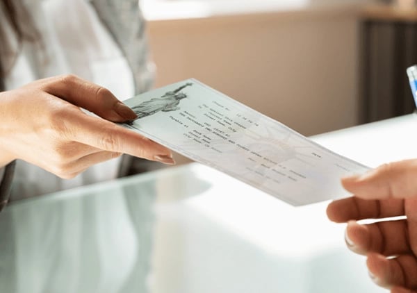 Bank clerk handing a check to a customer across a counter